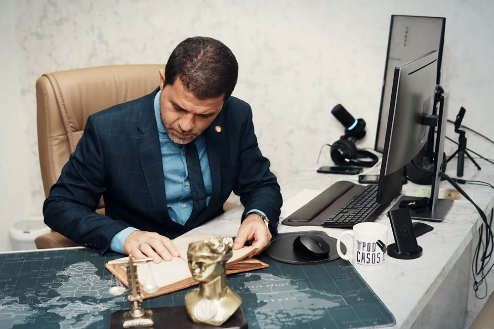 Dr. Márcio Lima da Silva lendo os autos de um processo à mesa do escritório.